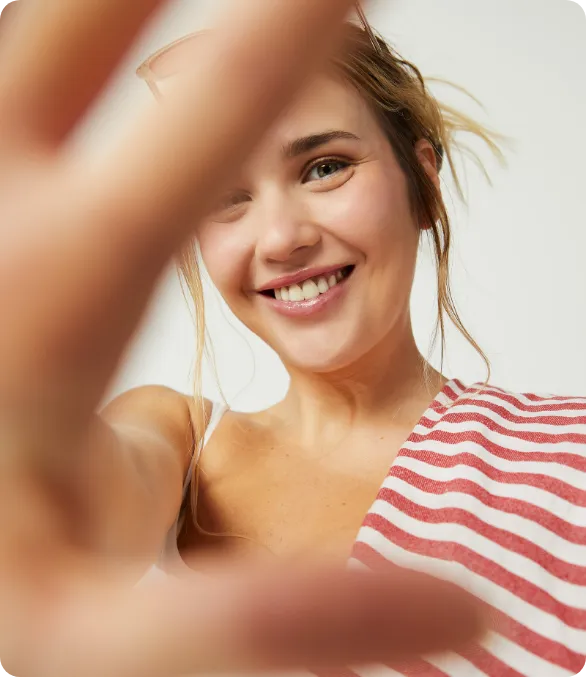 Modella sorridente con i capelli biondi raccolti e gli occhiali da sole sulla testa