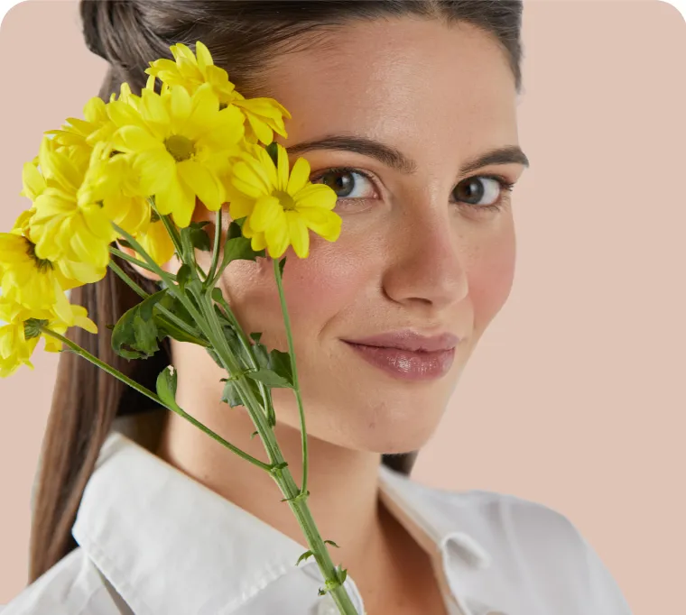 Foto di copertina del magazine in cui è presente una modella con i capelli castani semiraccolti che tiene dei fiori gialli davanti al viso